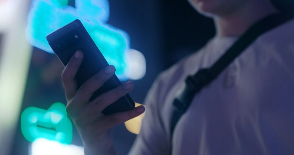 Manos sujetando un teléfono móvil con la pantalla encendida, imagen sobre el ciberacoso
